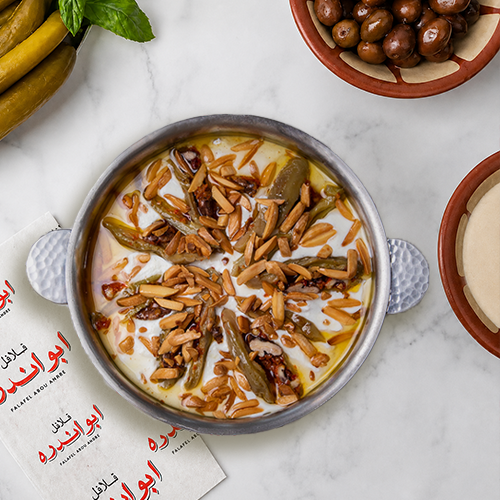 Traditional Fattet Makdous from Falafel Abou Andre served in a plate, featuring baby eggplants layer in garlic yogurt sauce, topped with toasted pine nuts,or silvered almonds.