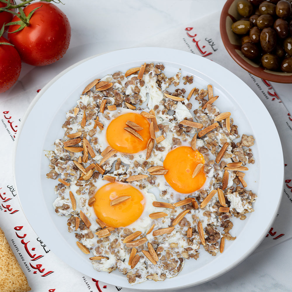"Freshly prepared eggs with qawarma topped in nuts with traditional Lebanese lamb that comes with Tomatoes, Radishes, Onions, Refreshing mint, Pickled cucumbers and turnips, lebanese olives and break at Falafel Abou Andre''.