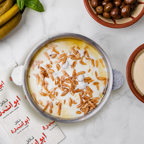 "Traditional Lebanese Fattet Hummus with toasted nuts at Falafel Abou Andre, made with creamy yogurt, tender chickpeas, crispy pita, and roasted almonds."
