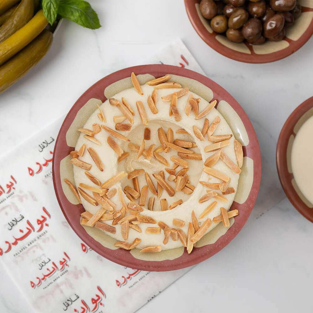 "Freshly prepared hummus with roasted nuts, a traditional Lebanese chickpea dip served at Falafel Abou Andre."